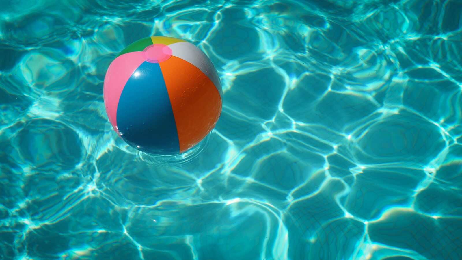 A beachball floats in the crystal clear water of your fiberglass pool